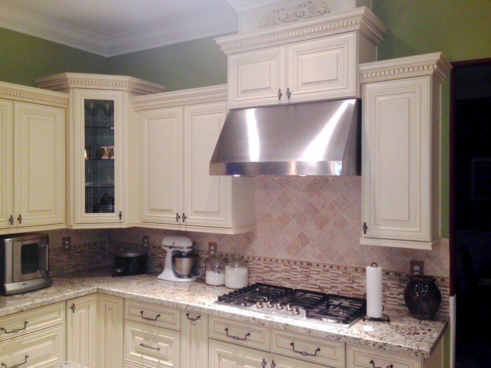 Bild på ett stort funkis vit vitt kök, med luckor med infälld panel, vita skåp, granitbänkskiva, vitt stänkskydd, stänkskydd i porslinskakel, rostfria vitvaror och en köksö