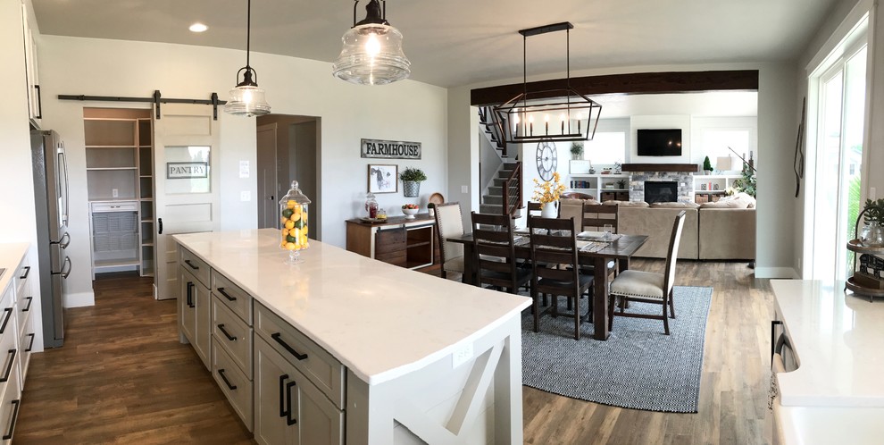 Foto på ett stort lantligt linjärt kök med öppen planlösning, med en rustik diskho, skåp i shakerstil, vita skåp, marmorbänkskiva, vitt stänkskydd, stänkskydd i tunnelbanekakel, rostfria vitvaror, vinylgolv, en köksö och brunt golv