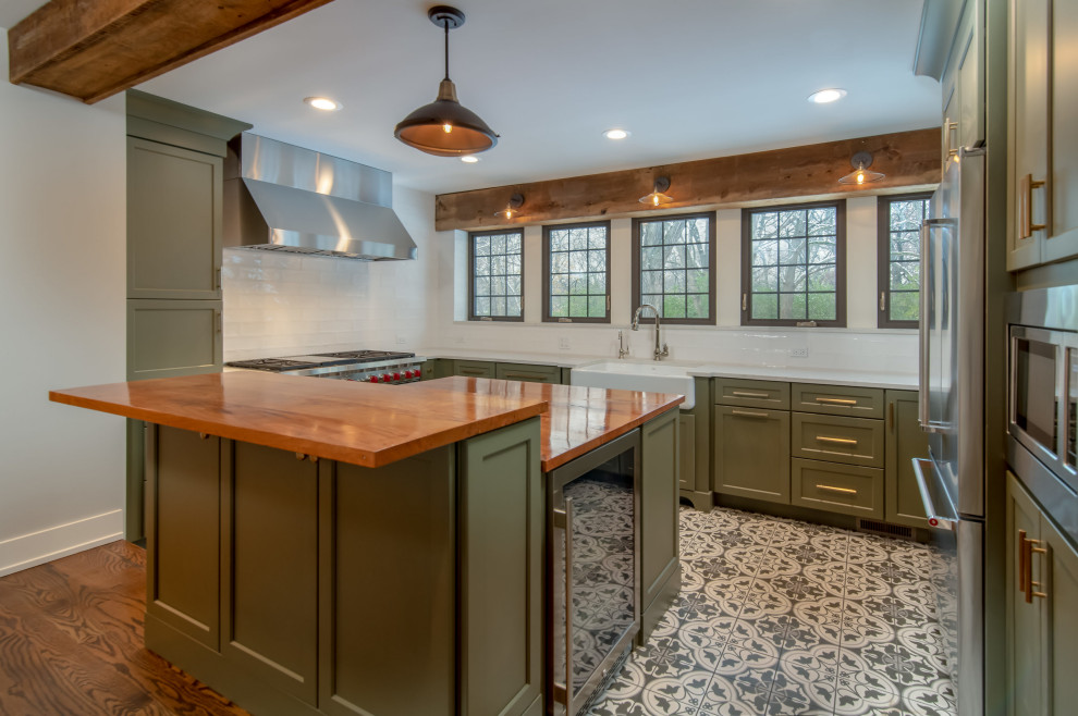 Enclosed kitchen - mid-sized rustic u-shaped porcelain tile and multicolored floor enclosed kitchen idea in Chicago with a farmhouse sink, shaker cabinets, green cabinets, wood countertops, white backsplash, subway tile backsplash, stainless steel appliances, an island and brown countertops