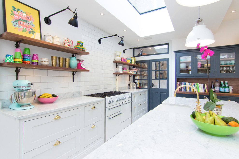 This is an example of a classic kitchen in London with a belfast sink, shaker cabinets, white cabinets, white splashback, metro tiled splashback and white appliances.