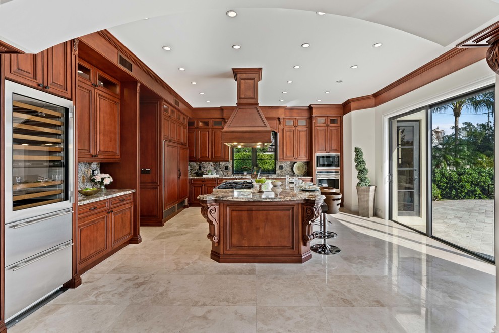 Kitchen - huge mediterranean l-shaped gray floor kitchen idea in Miami with raised-panel cabinets, medium tone wood cabinets, stainless steel appliances and an island