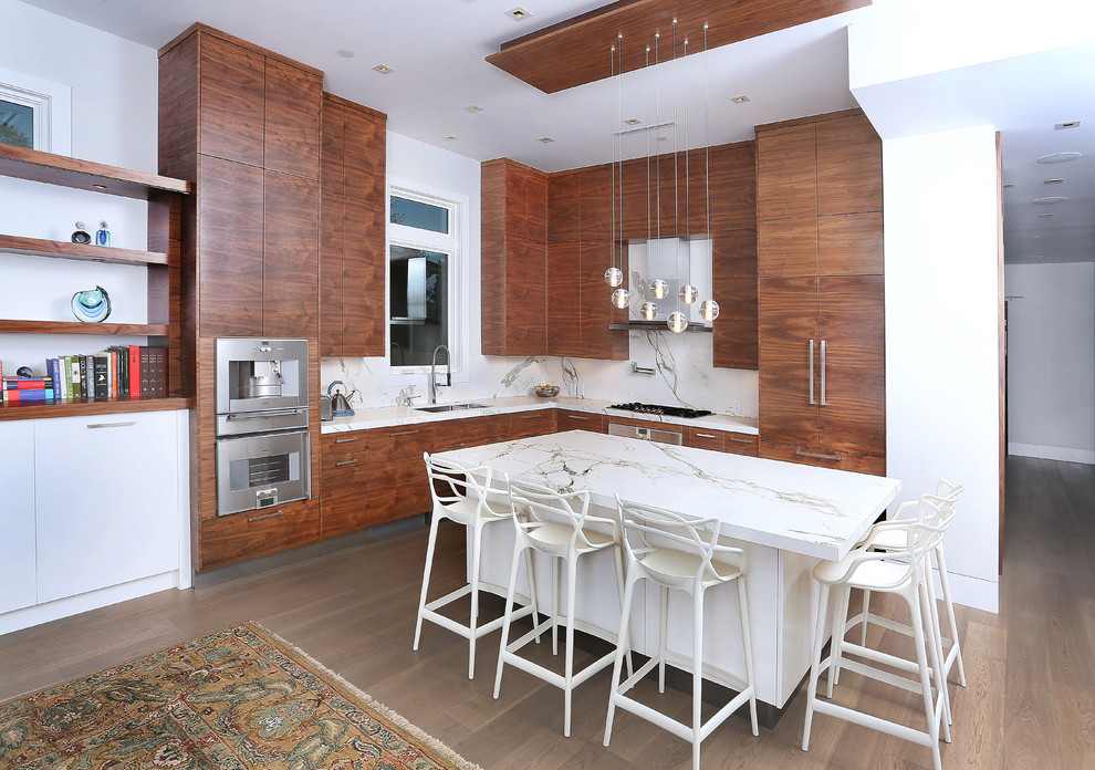 Huge trendy l-shaped light wood floor and brown floor open concept kitchen photo in Vancouver with a drop-in sink, flat-panel cabinets, medium tone wood cabinets, white backsplash, stainless steel appliances and an island
