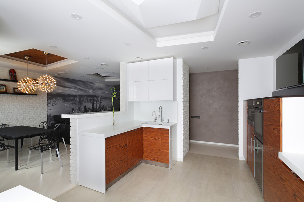 Foto de cocina contemporánea con fregadero integrado, armarios con paneles lisos, puertas de armario de madera oscura, salpicadero blanco y electrodomésticos negros