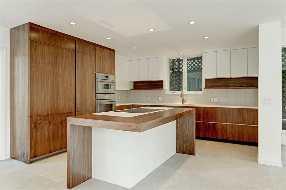 Photo of a small contemporary l-shaped open plan kitchen in Houston with a submerged sink, flat-panel cabinets, medium wood cabinets, white splashback, glass tiled splashback, stainless steel appliances, porcelain flooring, an island, grey floors, white worktops and engineered stone countertops.