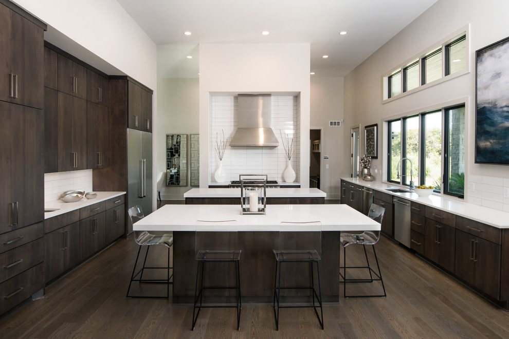 Photo of a large contemporary u-shaped open plan kitchen in Wichita with a submerged sink, flat-panel cabinets, dark wood cabinets, white splashback, stainless steel appliances, dark hardwood flooring, multiple islands, composite countertops and porcelain splashback.