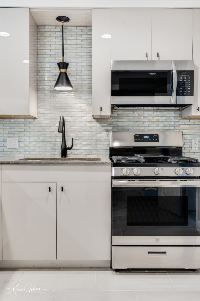 Small trendy l-shaped ceramic tile and white floor eat-in kitchen photo in Other with an undermount sink, flat-panel cabinets, beige cabinets, limestone countertops, gray backsplash, glass tile backsplash, stainless steel appliances, a peninsula and gray countertops