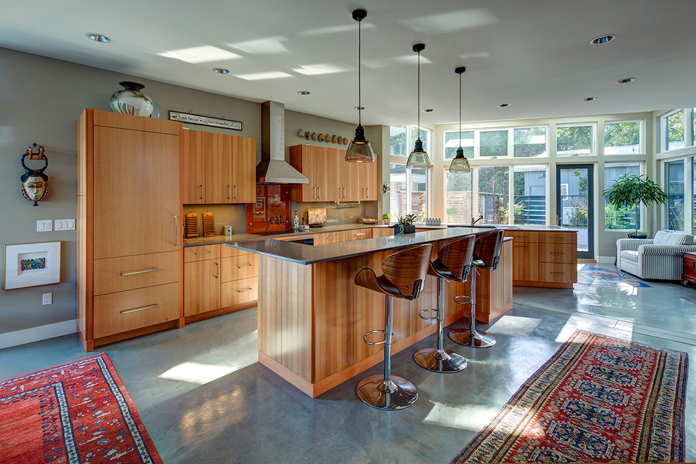 Modern inredning av ett mellanstort kök, med en undermonterad diskho, släta luckor, skåp i ljust trä, bänkskiva i kvarts, rostfria vitvaror, betonggolv och en köksö