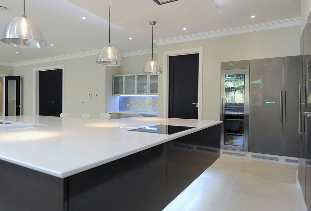 Inspiration for an expansive contemporary u-shaped open plan kitchen in London with an integrated sink, flat-panel cabinets, dark wood cabinets, composite countertops, metallic splashback, glass sheet splashback, integrated appliances, porcelain flooring and an island.
