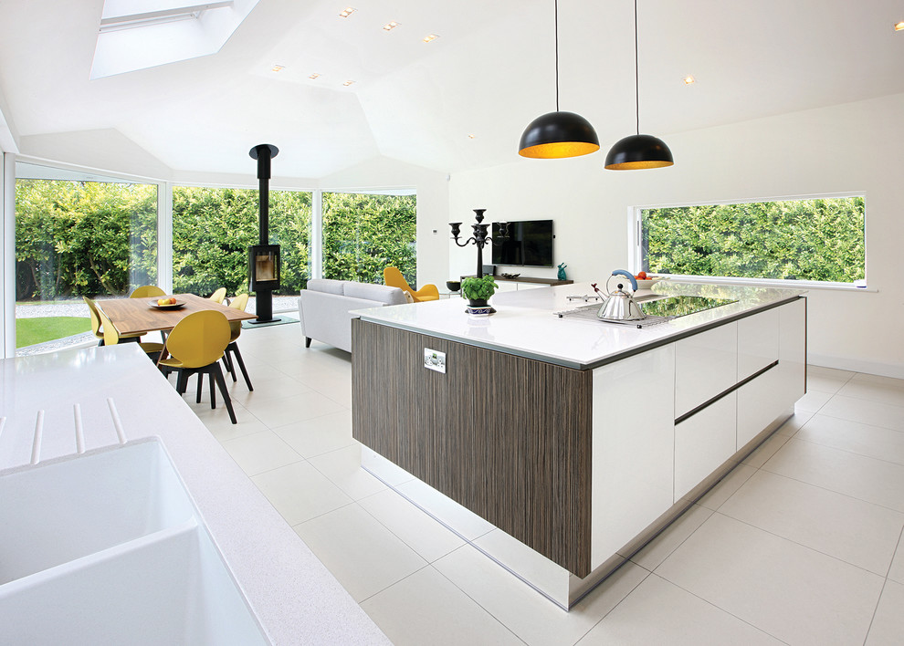 Contemporary galley open plan kitchen in West Midlands with flat-panel cabinets, white cabinets and an island.