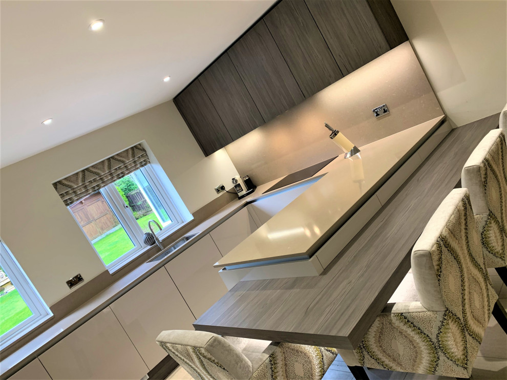 Medium sized contemporary u-shaped kitchen/diner in Other with a single-bowl sink, flat-panel cabinets, medium wood cabinets, quartz worktops, black appliances and vinyl flooring.