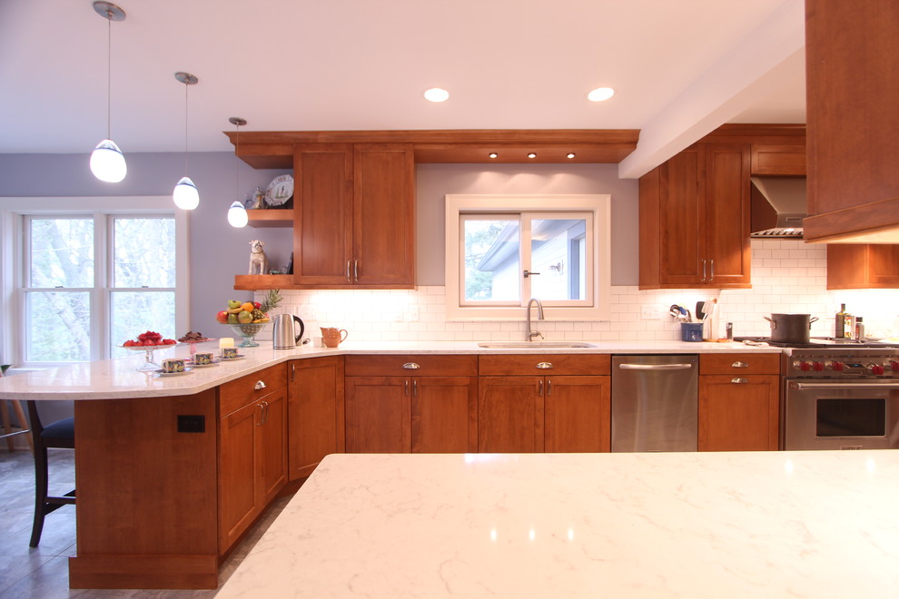 Eat-in kitchen - large transitional u-shaped vinyl floor eat-in kitchen idea in Other with an undermount sink, recessed-panel cabinets, medium tone wood cabinets, quartz countertops, white backsplash, ceramic backsplash, stainless steel appliances and a peninsula