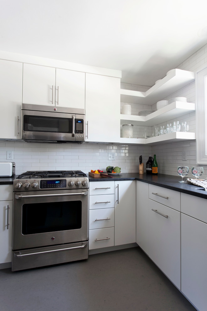 Inredning av ett modernt avskilt, litet u-kök, med en undermonterad diskho, vita skåp, vitt stänkskydd, stänkskydd i keramik, rostfria vitvaror, linoleumgolv och en köksö