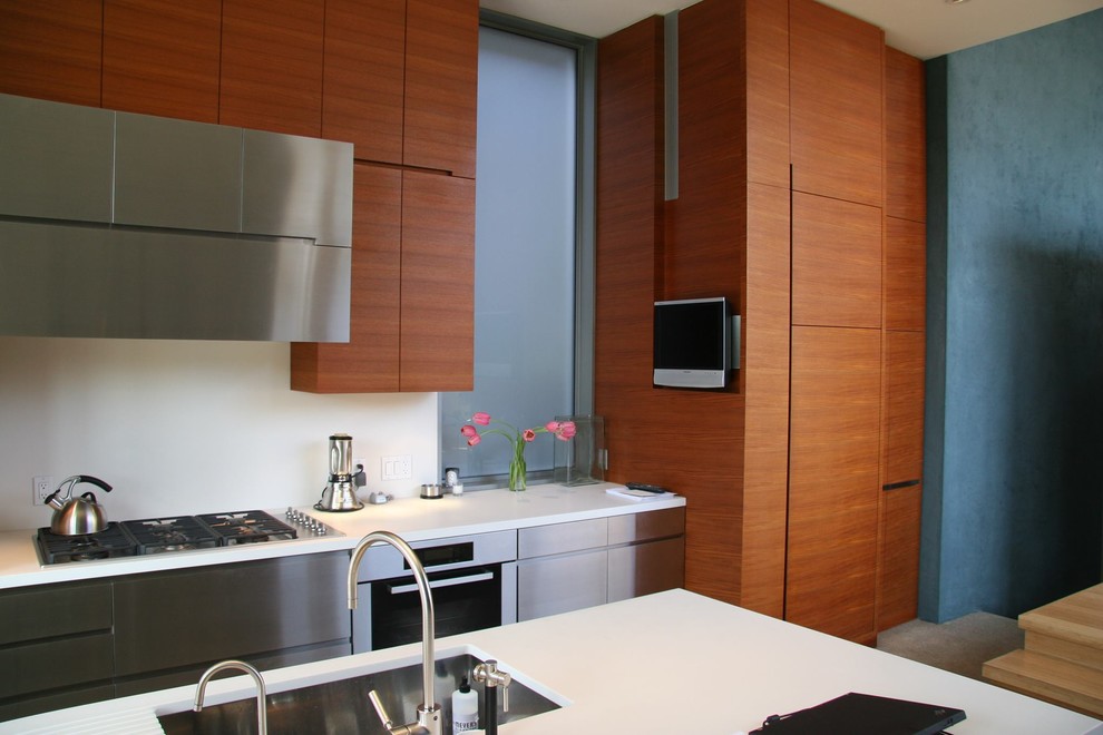 Immagine di una cucina minimalista con lavello sottopiano, paraspruzzi bianco e elettrodomestici in acciaio inossidabile
