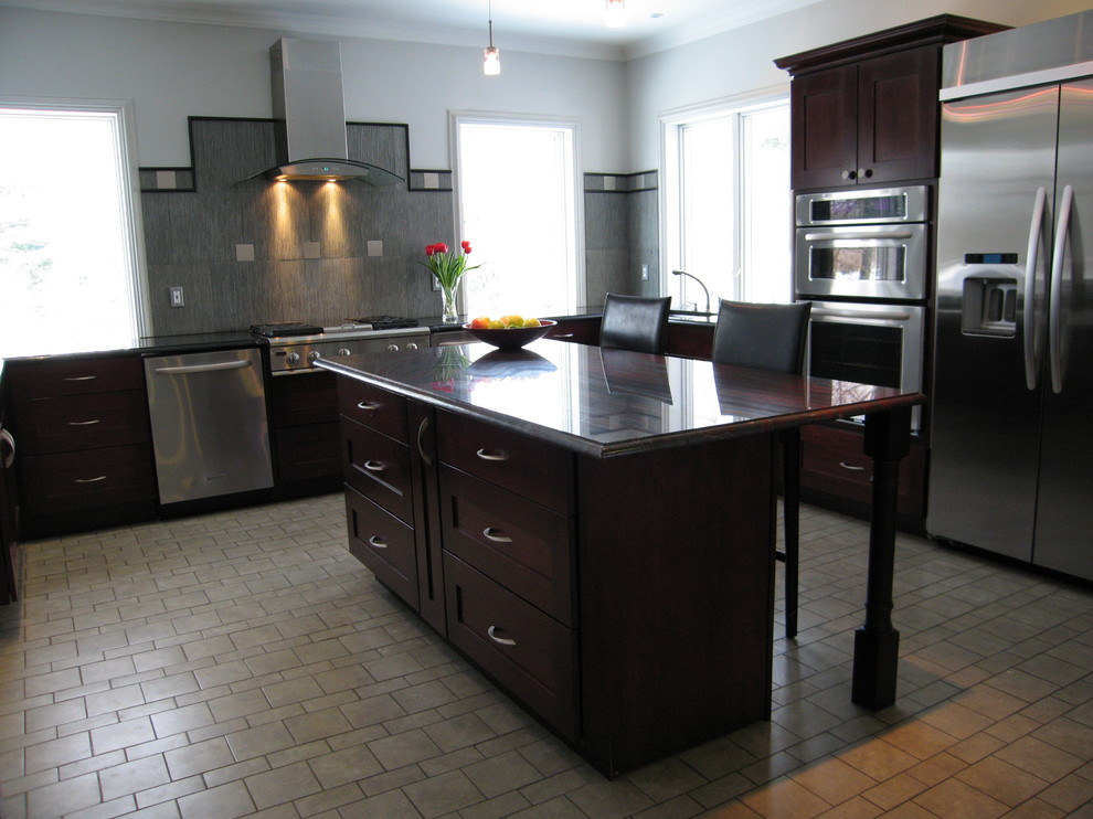 Bild på ett stort funkis u-kök, med en undermonterad diskho, luckor med infälld panel, granitbänkskiva, grått stänkskydd, stänkskydd i stenkakel, rostfria vitvaror, klinkergolv i keramik och en köksö