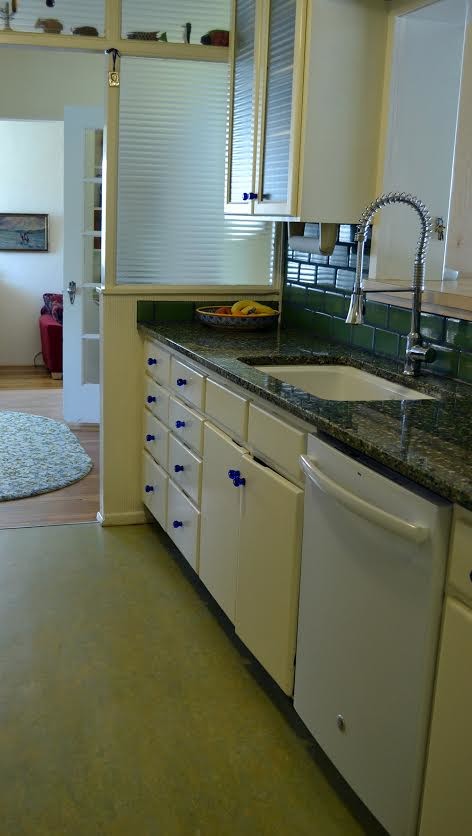 フェニックスにある中くらいなトラディショナルスタイルのおしゃれなII型キッチン (アンダーカウンターシンク、ガラス扉のキャビネット、黄色いキャビネット、御影石カウンター、緑のキッチンパネル、サブウェイタイルのキッチンパネル、白い調理設備、リノリウムの床) の写真