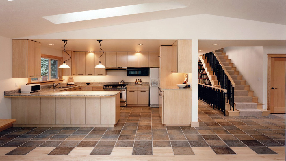 Foto på ett funkis kök, med en undermonterad diskho, släta luckor, skåp i ljust trä, granitbänkskiva, stänkskydd i sten, vita vitvaror, skiffergolv och en halv köksö