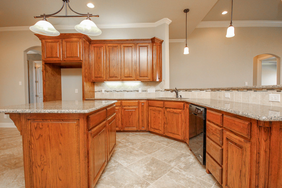 Example of a large classic l-shaped porcelain tile eat-in kitchen design in Dallas with medium tone wood cabinets, beige backsplash, an island, an undermount sink, raised-panel cabinets, granite countertops, stone tile backsplash and stainless steel appliances