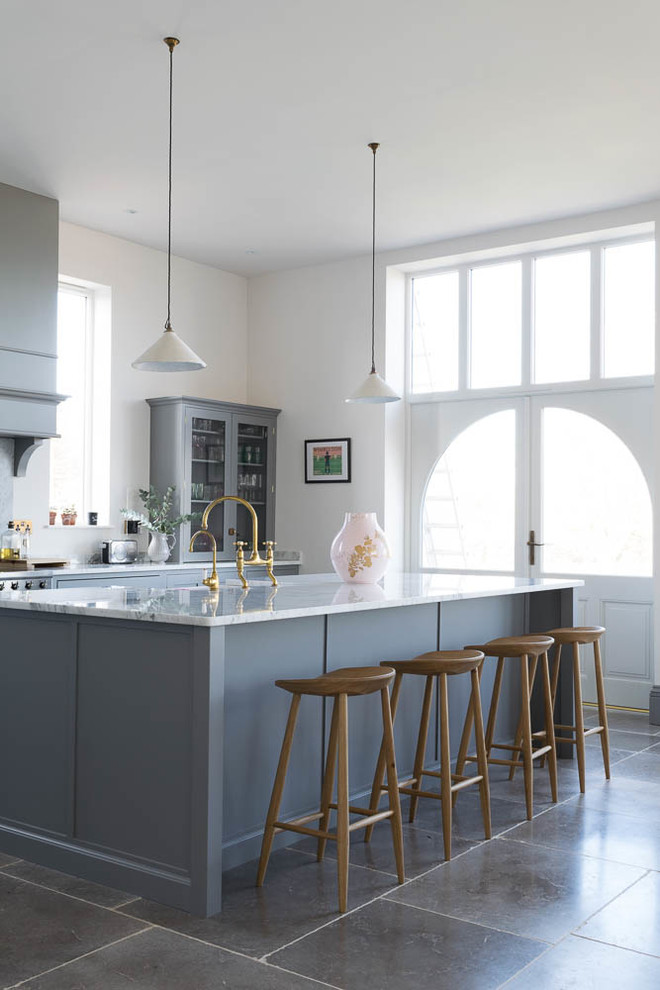 Traditional galley kitchen/diner in Other with a belfast sink, recessed-panel cabinets, grey cabinets, white splashback, an island, grey floors and white worktops.