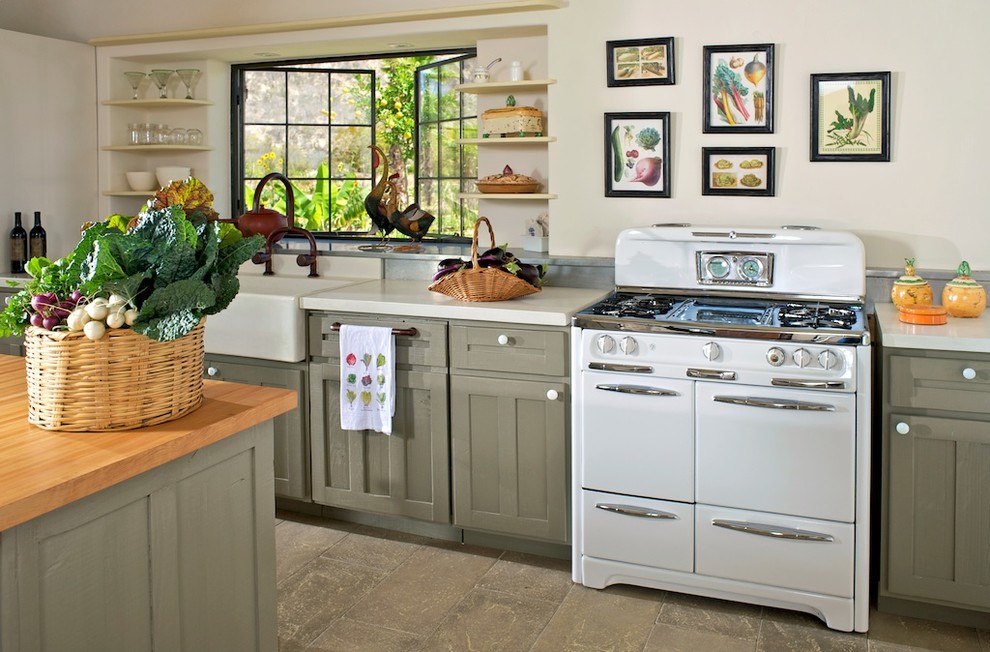 Bild på ett lantligt kök, med en rustik diskho, luckor med infälld panel, vita vitvaror, betonggolv, en köksö och grå skåp