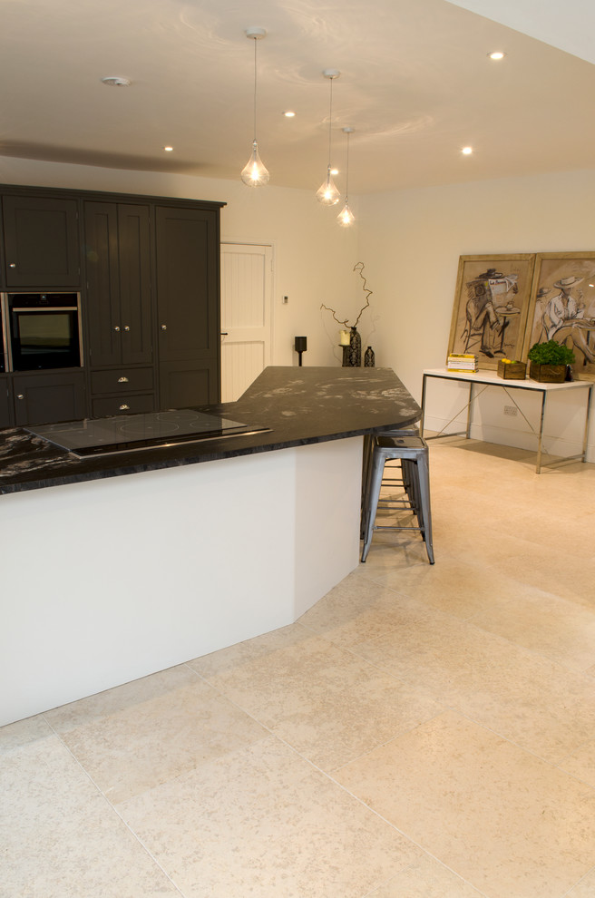 Large contemporary open plan kitchen in Other with limestone flooring and an island.