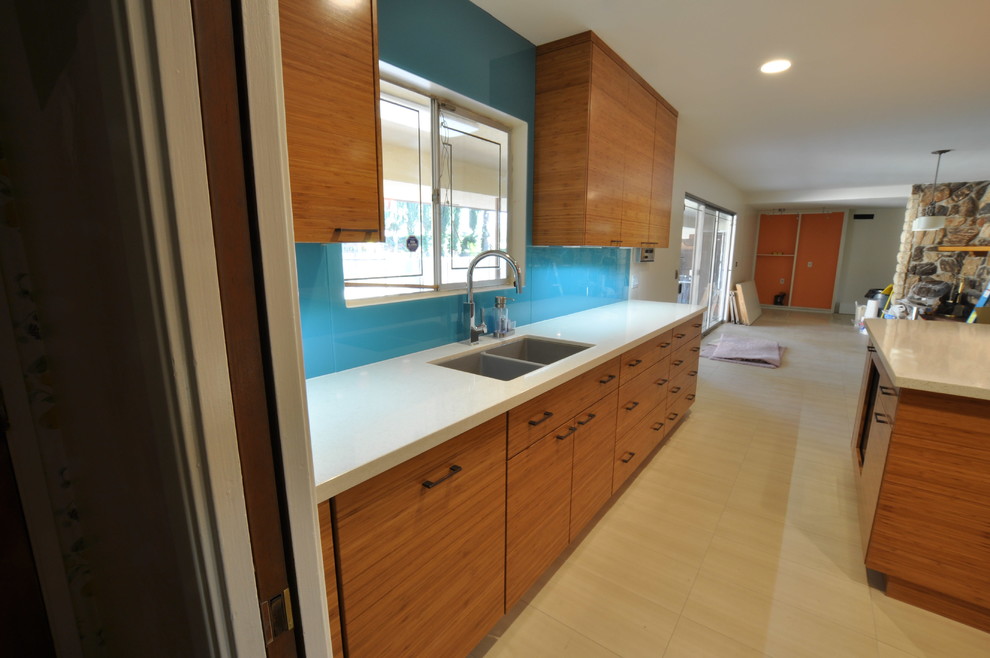 Example of a mid-sized minimalist u-shaped porcelain tile open concept kitchen design in Los Angeles with an undermount sink, flat-panel cabinets, medium tone wood cabinets, quartz countertops, blue backsplash, glass sheet backsplash, stainless steel appliances and an island