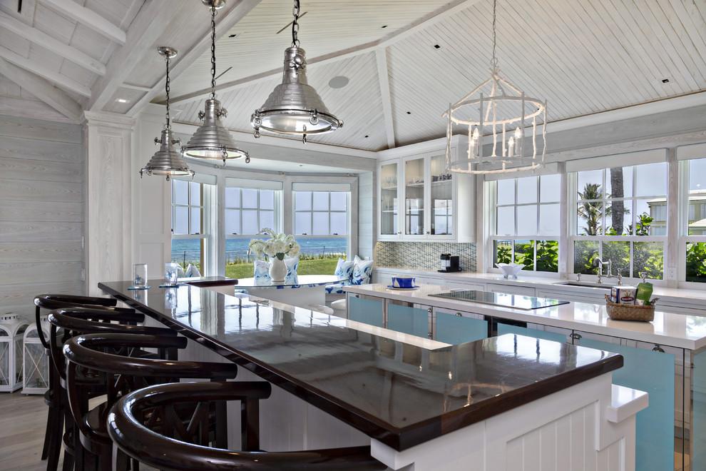 На фото: кухня в морском стиле с стеклянными фасадами, барной стойкой, окном и эркером с