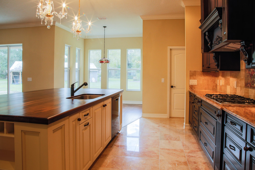 This is an example of a large traditional galley kitchen in Tampa with a submerged sink, dark wood cabinets, wood worktops, beige splashback, black appliances, marble flooring and an island.