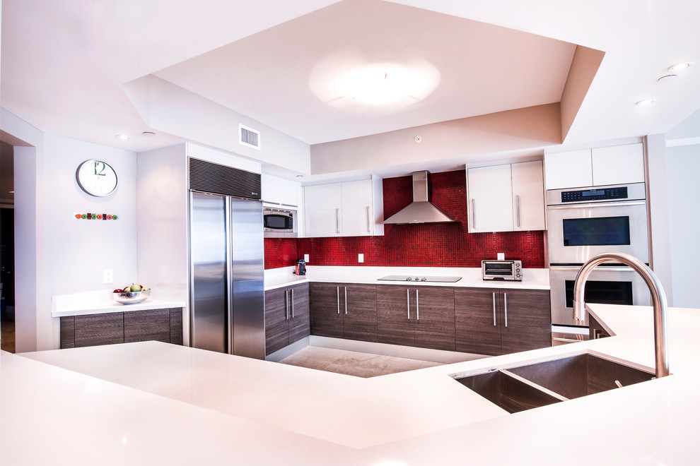 Geräumige Moderne Wohnküche in U-Form mit flächenbündigen Schrankfronten, dunklen Holzschränken, Laminat-Arbeitsplatte, Küchenrückwand in Rot, Küchengeräten aus Edelstahl und Kücheninsel in Miami