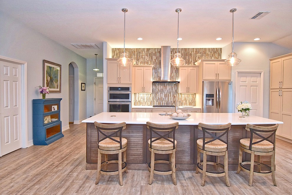 Expansive classic open plan kitchen in Other with a submerged sink, shaker cabinets, white cabinets, engineered stone countertops, multi-coloured splashback, glass tiled splashback, stainless steel appliances, vinyl flooring, an island, brown floors and white worktops.