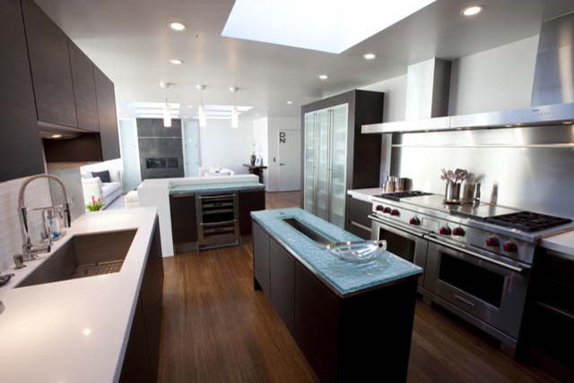 Example of a mid-sized trendy u-shaped bamboo floor kitchen design in San Luis Obispo with an undermount sink, flat-panel cabinets, dark wood cabinets, quartz countertops, white backsplash, ceramic backsplash, stainless steel appliances and an island