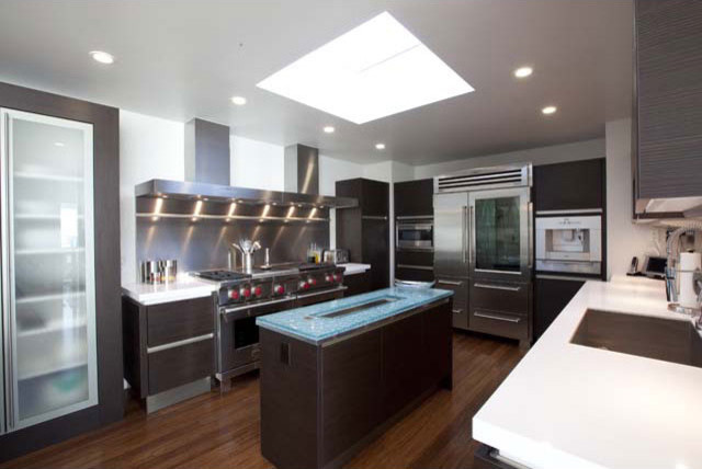 Mid-sized trendy u-shaped bamboo floor kitchen photo in San Luis Obispo with an undermount sink, flat-panel cabinets, dark wood cabinets, quartz countertops, white backsplash and stainless steel appliances
