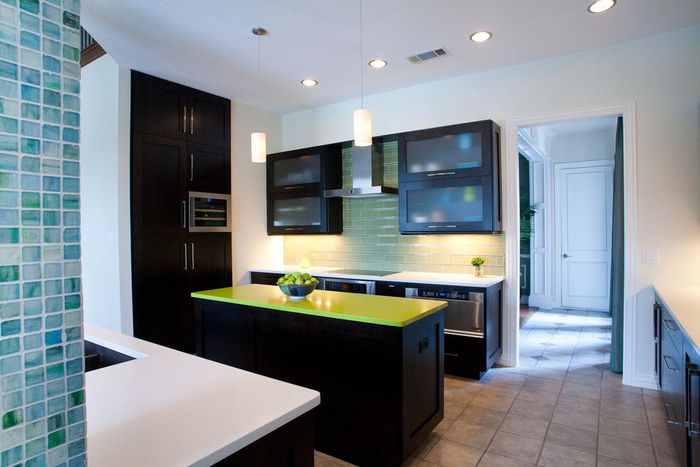 Geschlossene Moderne Küche mit Unterbauwaschbecken, Glasfronten, dunklen Holzschränken, Küchenrückwand in Grün und Küchengeräten aus Edelstahl in Dallas