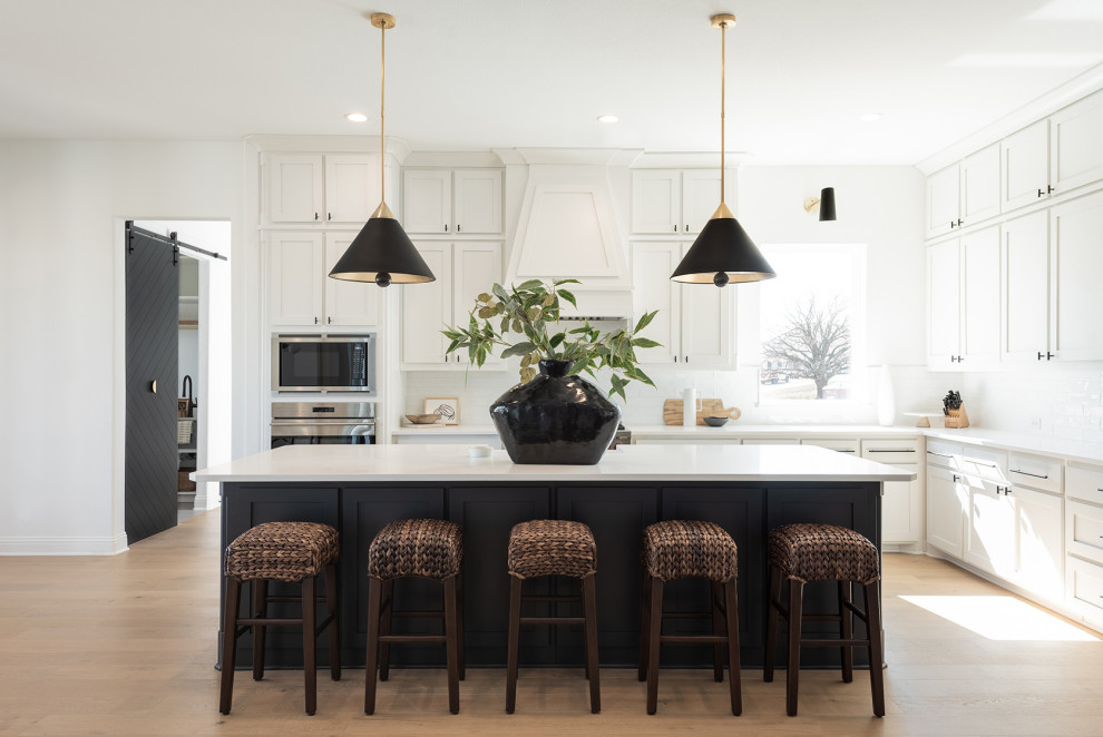 Example of a large transitional l-shaped light wood floor and beige floor open concept kitchen design in Dallas with shaker cabinets, white cabinets, quartzite countertops, white backsplash, stainless steel appliances, an island and white countertops
