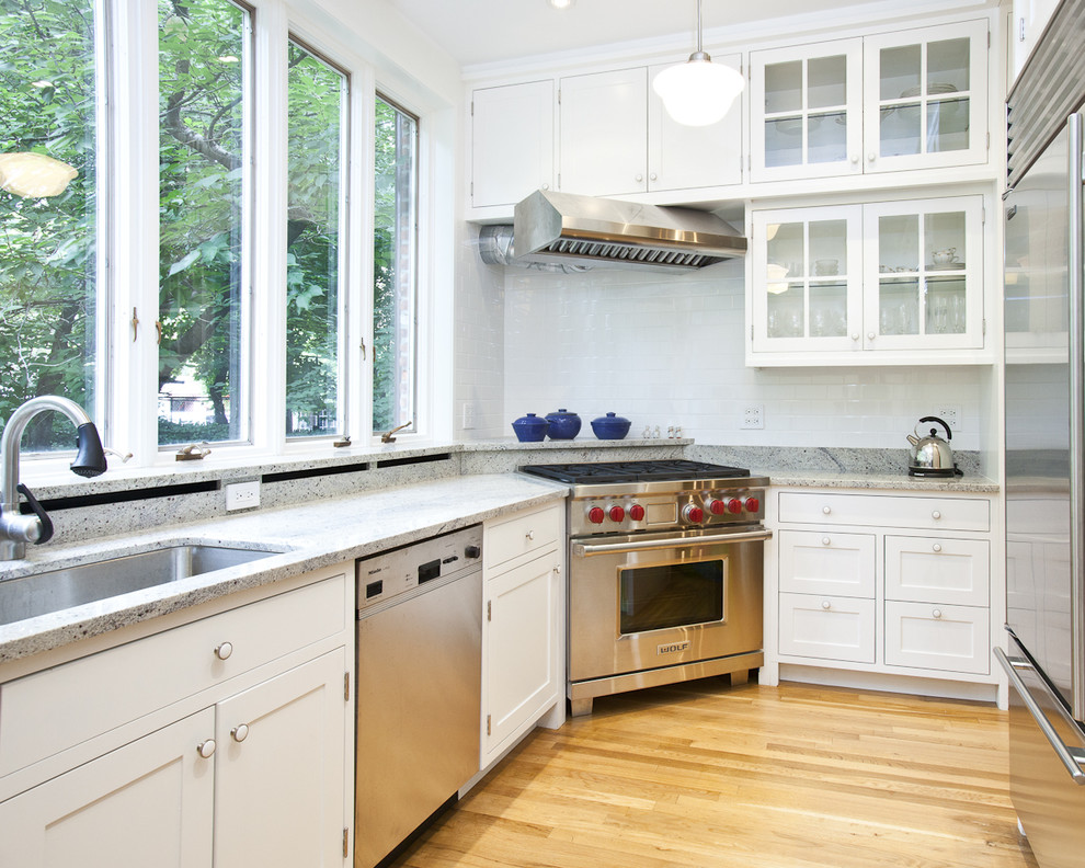Photo of a contemporary kitchen in New York with glass-front cabinets and stainless steel appliances.