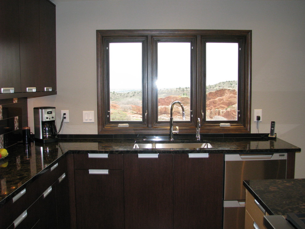 Modern inredning av ett mellanstort kök, med en undermonterad diskho, släta luckor, granitbänkskiva, svart stänkskydd, stänkskydd i metallkakel, rostfria vitvaror, kalkstensgolv och en köksö