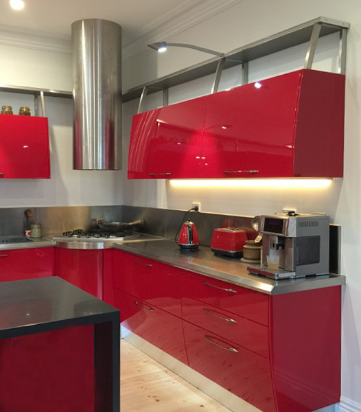 Modern inredning av ett mellanstort kök, med en dubbel diskho, luckor med upphöjd panel, röda skåp, bänkskiva i kvartsit, stänkskydd med metallisk yta, rostfria vitvaror, ljust trägolv och en köksö