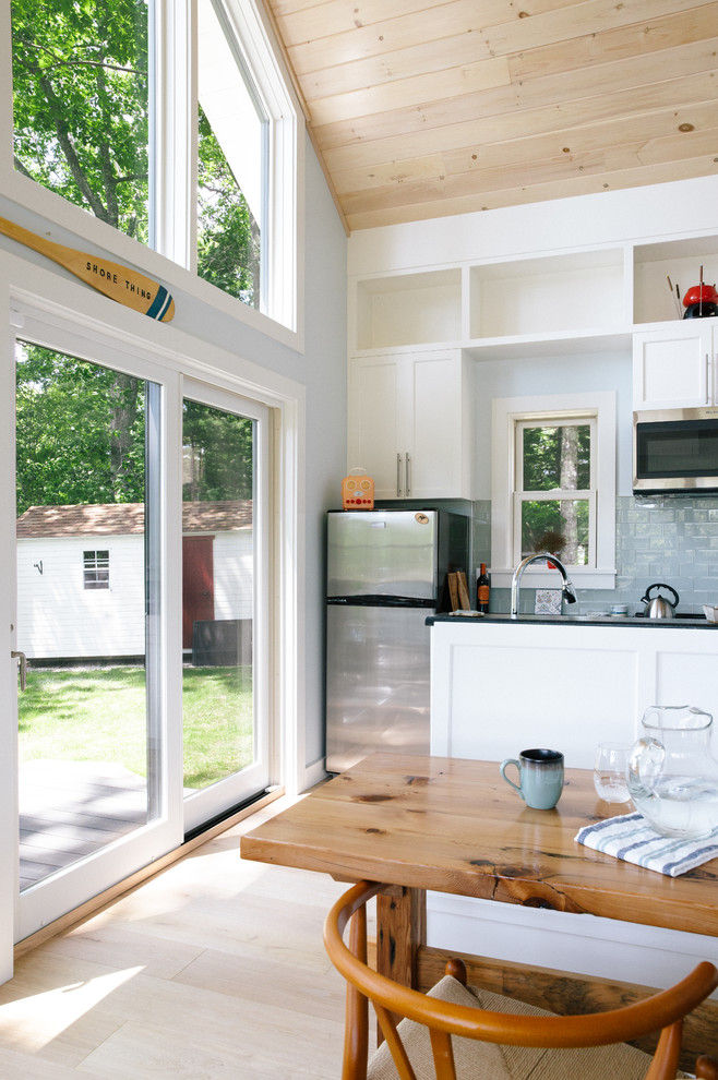 Exempel på ett litet skandinaviskt svart svart kök, med en undermonterad diskho, skåp i shakerstil, vita skåp, granitbänkskiva, blått stänkskydd, stänkskydd i tunnelbanekakel, rostfria vitvaror, ljust trägolv, en köksö och beiget golv