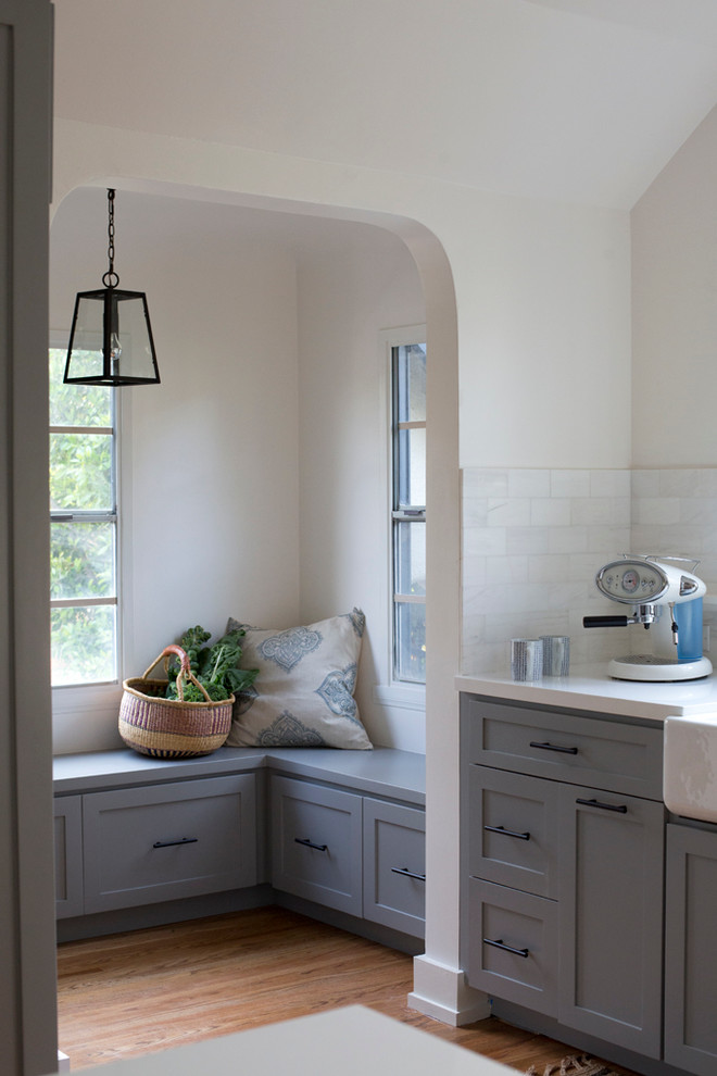 Elegant u-shaped eat-in kitchen photo in Los Angeles with a farmhouse sink, shaker cabinets, gray cabinets, white backsplash, subway tile backsplash and stainless steel appliances
