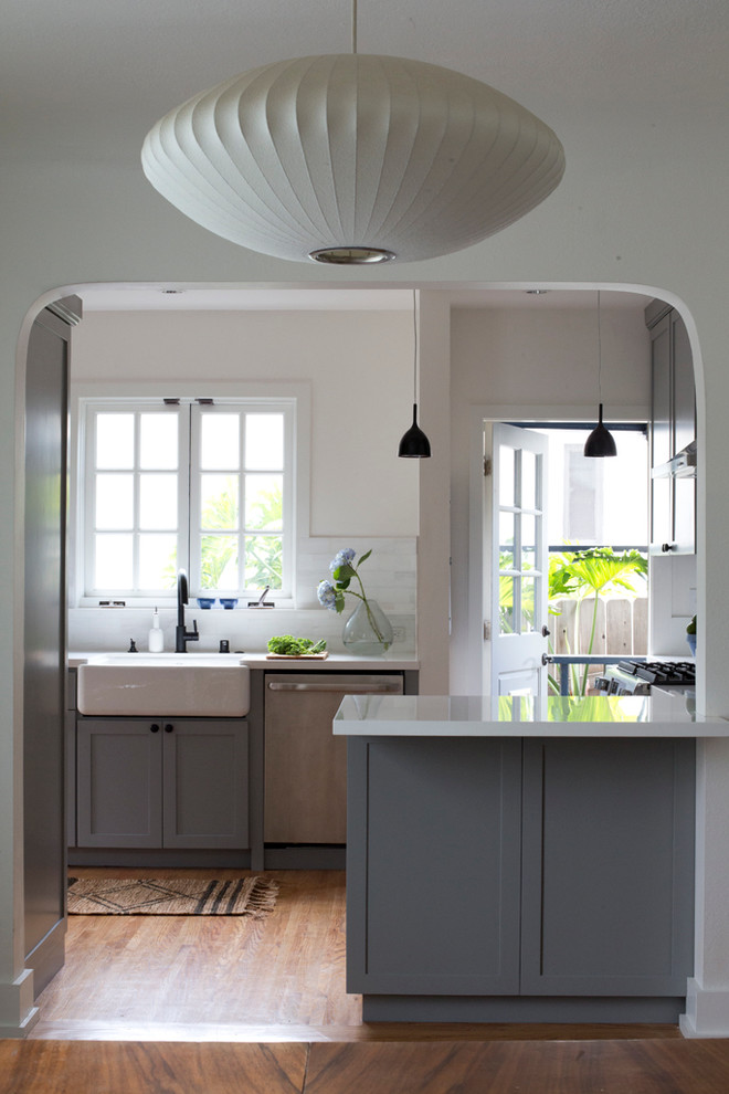 Inspiration for a timeless u-shaped eat-in kitchen remodel in Los Angeles with a farmhouse sink, shaker cabinets, gray cabinets, white backsplash, subway tile backsplash and stainless steel appliances