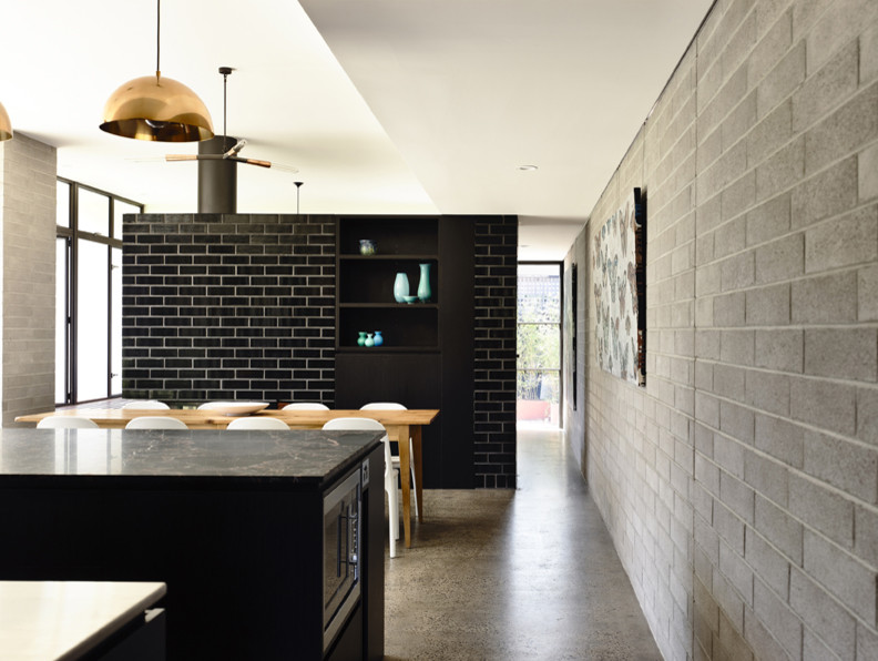 Inspiration för ett mellanstort funkis kök, med släta luckor, svarta skåp, granitbänkskiva, rostfria vitvaror, betonggolv och en köksö