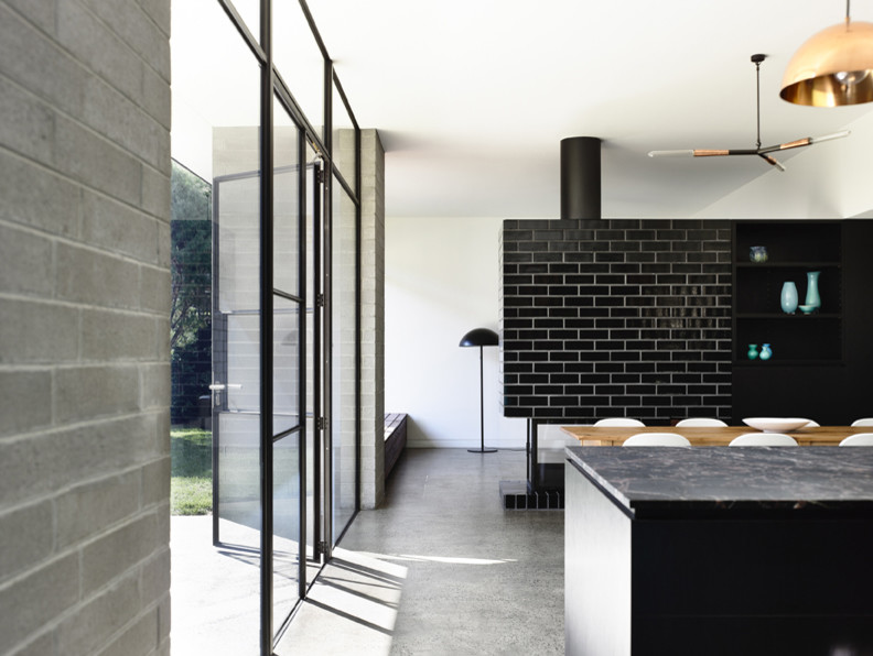 Zweizeilige, Mittelgroße Moderne Wohnküche mit flächenbündigen Schrankfronten, schwarzen Schränken, Granit-Arbeitsplatte, Betonboden und Kücheninsel in Melbourne