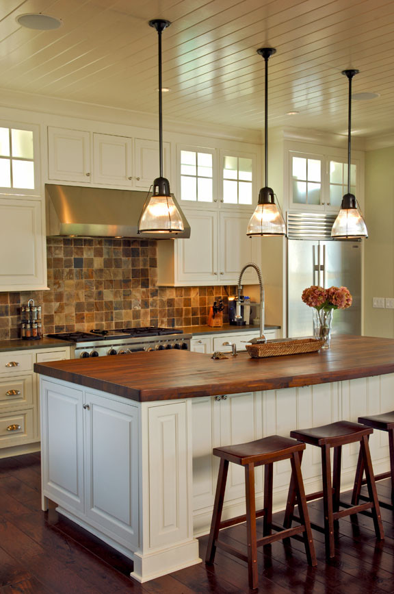 Immagine di una cucina costiera con ante bianche, top in legno, paraspruzzi con piastrelle in pietra e elettrodomestici in acciaio inossidabile