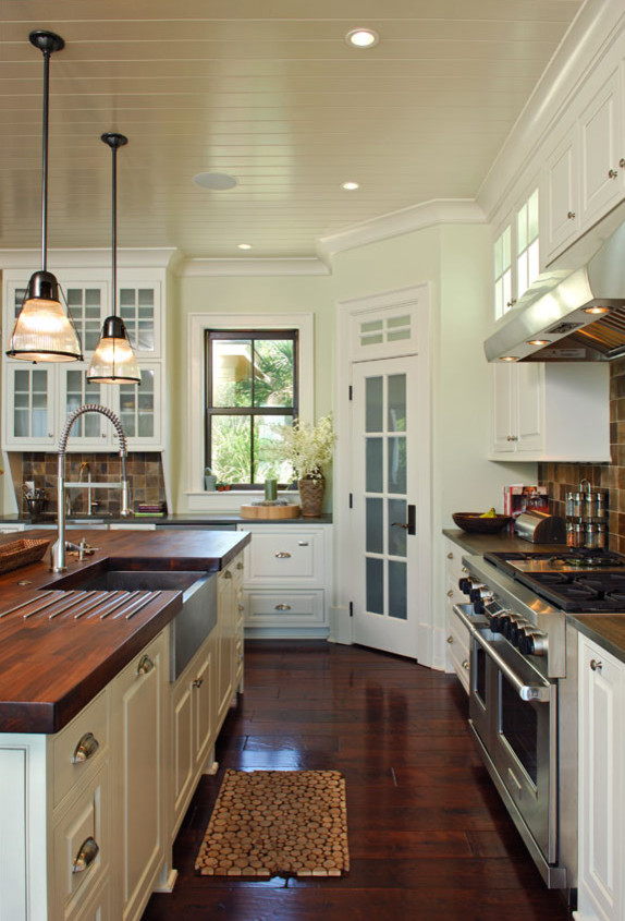 Inspiration for a coastal kitchen remodel in Charleston with beaded inset cabinets, white cabinets, wood countertops, stone tile backsplash, stainless steel appliances and an island