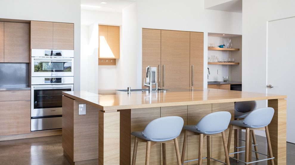 Exempel på ett modernt beige beige parallellkök, med en undermonterad diskho, släta luckor, skåp i ljust trä, grått stänkskydd, rostfria vitvaror, betonggolv, en köksö och grått golv
