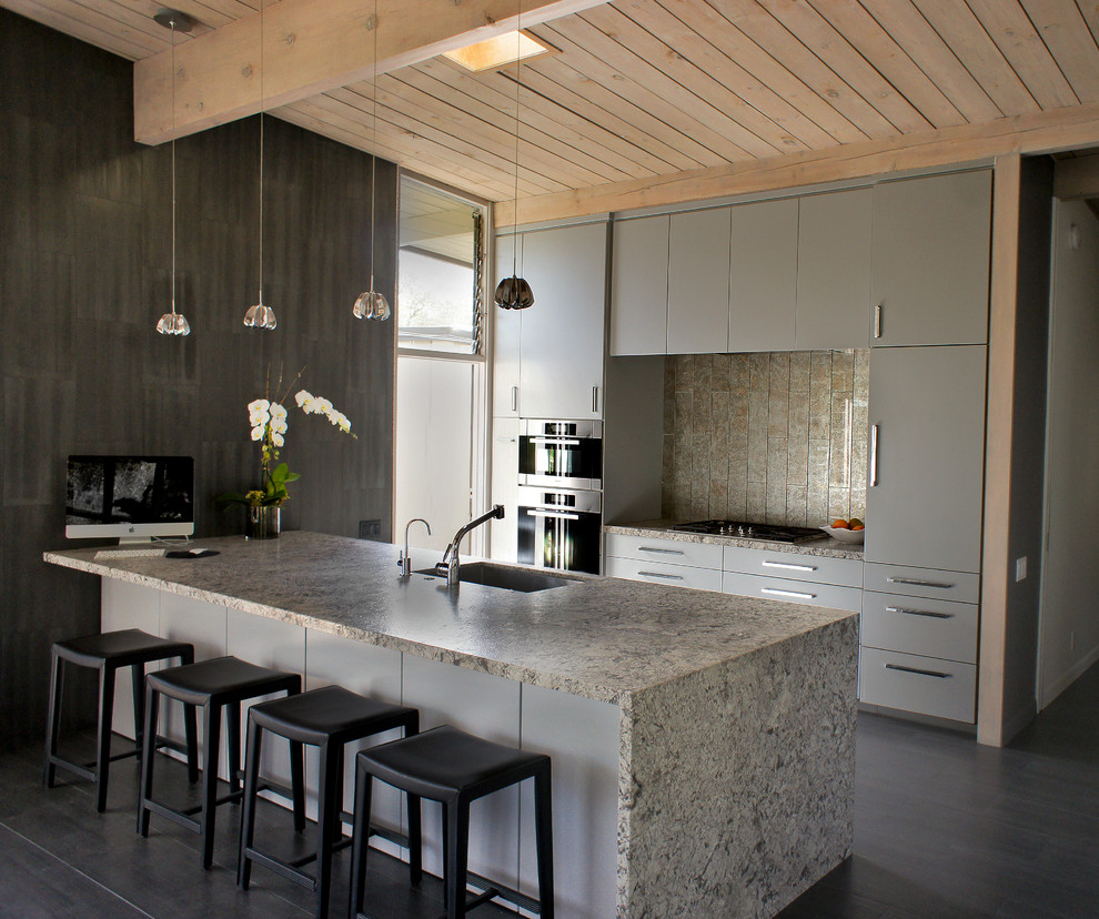 Imagen de cocina actual con encimera de granito, armarios con paneles lisos y puertas de armario grises