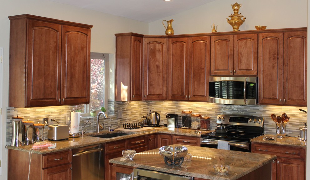 Bild på ett mellanstort vintage kök, med en undermonterad diskho, luckor med upphöjd panel, skåp i mellenmörkt trä, granitbänkskiva, flerfärgad stänkskydd, stänkskydd i glaskakel, rostfria vitvaror, klinkergolv i porslin och en köksö
