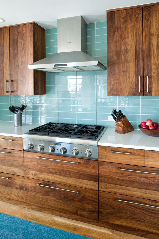 Idée de décoration pour une grande cuisine ouverte design en L et bois foncé avec un évier encastré, un placard à porte plane, un plan de travail en quartz, une crédence bleue, une crédence en carreau de verre, un électroménager en acier inoxydable, un sol en bois brun et îlot.