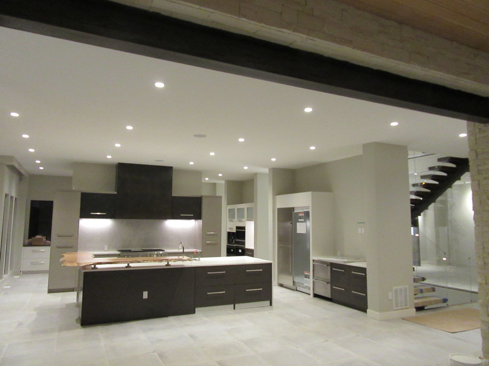 Exempel på ett mycket stort modernt kök och matrum, med en undermonterad diskho, släta luckor, bruna skåp, bänkskiva i kvarts, grått stänkskydd, stänkskydd i sten, rostfria vitvaror, klinkergolv i porslin, en köksö och grått golv