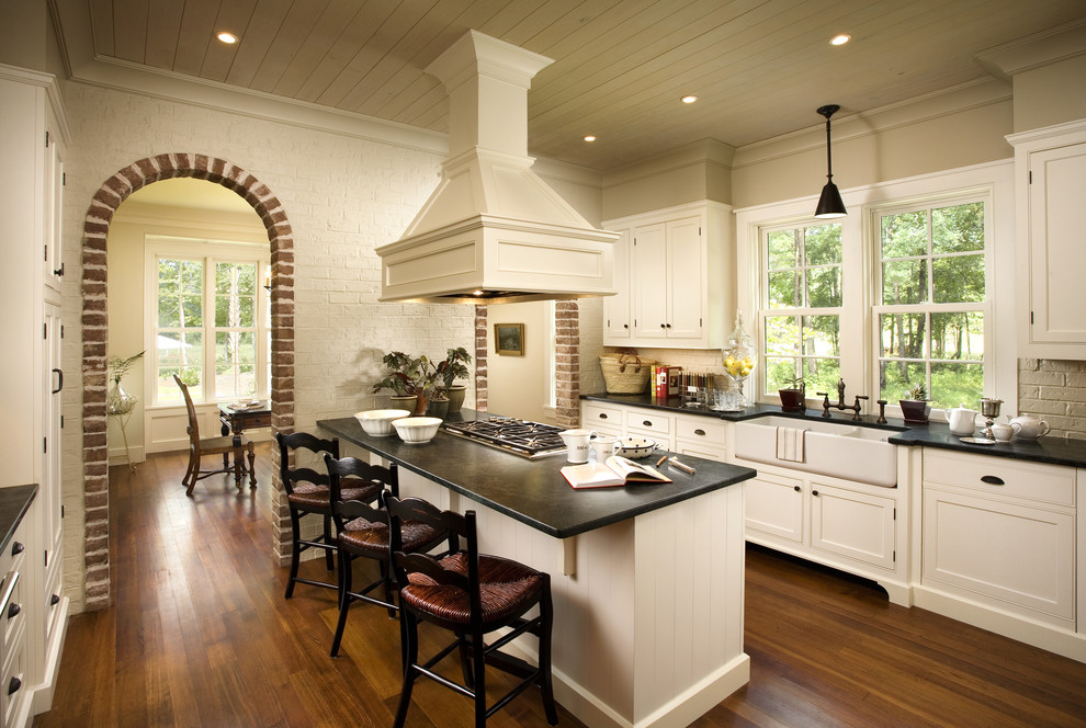 Zweizeilige Landhaus Küche mit Landhausspüle, Kassettenfronten, weißen Schränken, braunem Holzboden und Halbinsel in Atlanta