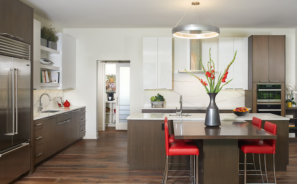 Example of a large trendy galley medium tone wood floor and brown floor eat-in kitchen design in Grand Rapids with an undermount sink, flat-panel cabinets, dark wood cabinets, quartz countertops, white backsplash, marble backsplash, stainless steel appliances, an island and white countertops